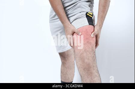 Closeup of sore knee on isolated background. Male holding his knee in pain on isolated Stock Photo