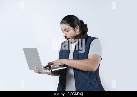 Man surprised looking at the computer he is holding on isolated Stock Photo