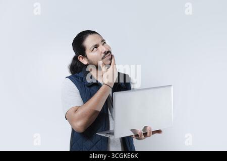 Thoughtful man with hand on chin using computer on isolated background. Man thinking holding a laptop on white background Stock Photo