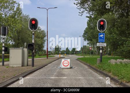 A "STOP" sign on the road with two red traffic lights and a "Camera Bewaking" (camera surveillance) sign, indicating controlled access. Utrecht, Nethe Stock Photo
