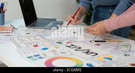 Creative UX and UI Design Process. Team members sketching and refining wireframes in a collaborative setting. Stock Photo