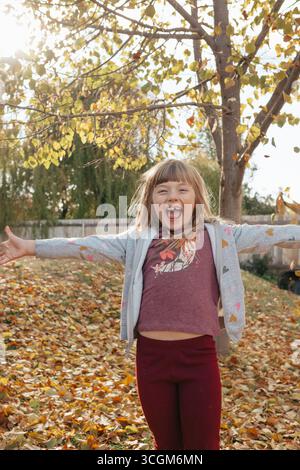Happy girl playing with yellow autumn leaves in park Stock Photo - Alamy