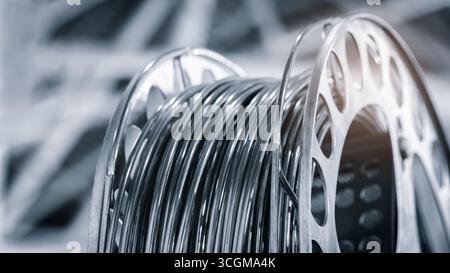 A close-up of the metal wire is shown. The wire is twisted on a spool, and this is a piece of wire used for welding and 3D printing. Stock Photo