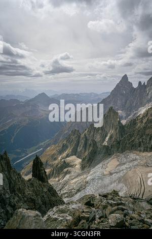 Jagged alpine peaks and glacier remains under cloudy sky in the Alps creating a dramatic high mountain landscape with rugged rocky ridges Stock Photo