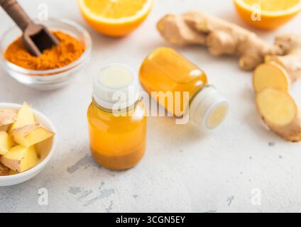 Turmeric energy shot immune drink with ginger root and ripe oranges on light background. Stock Photo