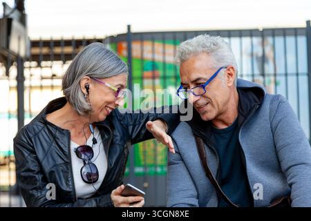 portrait of a woman and a man cheerfully discussing while sitting outdoors Stock Photo