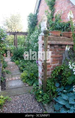 A winding pathway leads through a lush garden filled with colorful flowers and leafy plants, creating a tranquil atmosphere in the backyard. Stock Photo