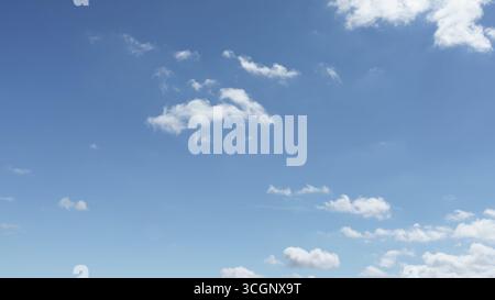 Small cumulus clouds scatter across a clear blue morning sky. Stock Photo