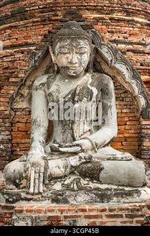 Yadana Hsemee Pagoda Complex Seated Buddha Statue Brick Wall Inwa Myanmar | INWA, Myanmar — A seated Buddha statue set into a brick wall at the Yadana Hsemee Pagoda Complex displays the bhumisparsha mudra, the earth-touching gesture marking the Buddha's enlightenment and the most common pose in Burmese image halls. The complex stands west of the old Ava Palace ruins in Apyin Sanyar Village, within the Inwa Ancient Cultural Heritage Zone. Stock Photo