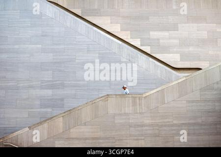 National Gallery Of Art East Building IM Pei Architecture Stairs Washington DC USA | WASHINGTON D.C., United States — A lone figure walks the angled marble stairway of the National Gallery of Art's East Building, a study in the geometric planning that defines I. M. Pei's design. Opened in 1978, the building shares the same pink-toned Tennessee marble as the neoclassical West Building next door and won Pei the Pritzker Prize in 1983. Stock Photo