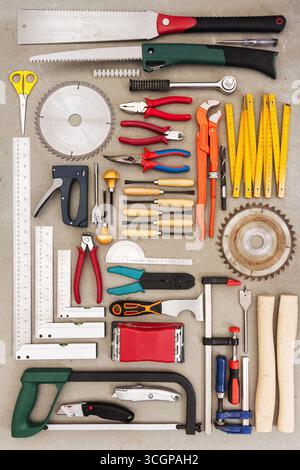 Flat lay of old hand tools on concrete background. Large collection of various rusty tools and bits arranged on concrete. Stock Photo