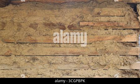 Insulation in the wall of a country house, tow between old planks or logs, an aged, dilapidated fragment of the outer wall of a barn or shed Stock Photo
