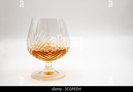 Cut crystal brandy glass filled with golden brandy on a plain white background, symbolising elegance, luxury, fine spirits, and sophisticated drinking Stock Photo