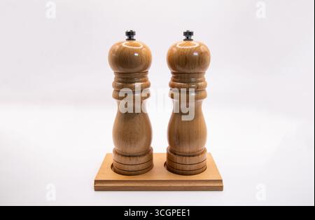 Wooden salt and pepper mills side by side on white background. Classic kitchen seasoning grinders, rustic style culinary tools for cooking, dining, an Stock Photo