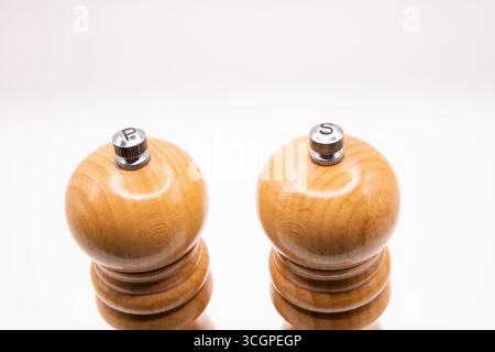 Wooden salt and pepper mills side by side on white background. Classic kitchen seasoning grinders, rustic style culinary tools for cooking, dining, an Stock Photo