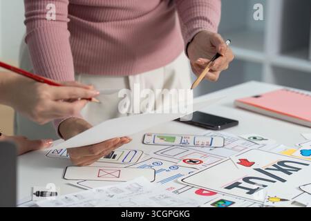 UX and UI Design Process. Close-up of hands reviewing sketches in a collaborative workspace. Stock Photo