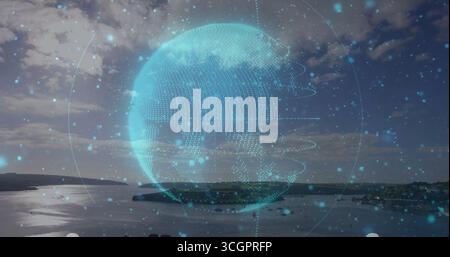 Floating holographic Earth globe hovering over coastal bay at dusk, with blue glowing dots Stock Photo