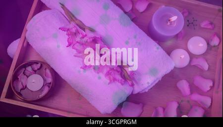 Displaying spa tray on treatment table, holding rolled white towels, pink gladiolus and lit candles Stock Photo