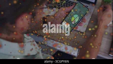 Holding smartphone, man analyzing data at office desk, with laptop, notebook and glowing particles Stock Photo