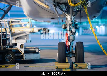 Aircraft nose wheel with red flag Remove Before Flight. Selective focus on airplane at airport. Stock Photo