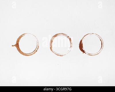 Three coffee rings and scattered droplets on a white background. Stock Photo