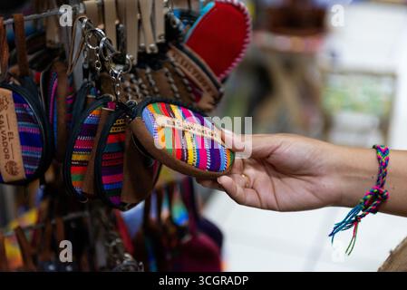A hand chooses a small, brightly colored coin purse with text 'El Salvador' on it. Stock Photo