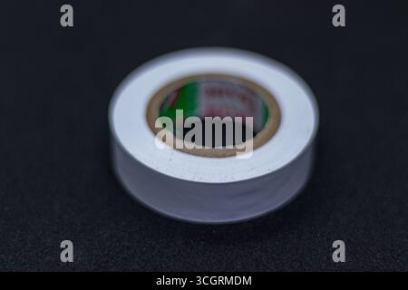 New White Electrical Tape Coil Isolated on Black Surface Stock Photo