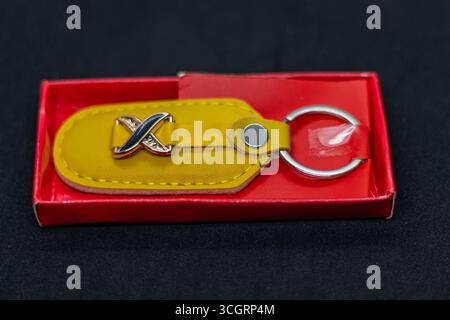 Stylish Yellow Leather Keychain with Metal X Emblem in Red Gift Box Stock Photo