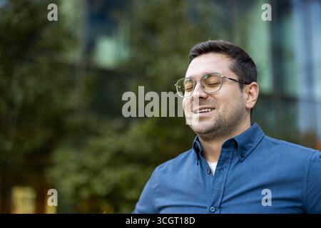 Young man in a serene setting closing his eyes, capturing a tranquil and joyful vibe. Stock Photo