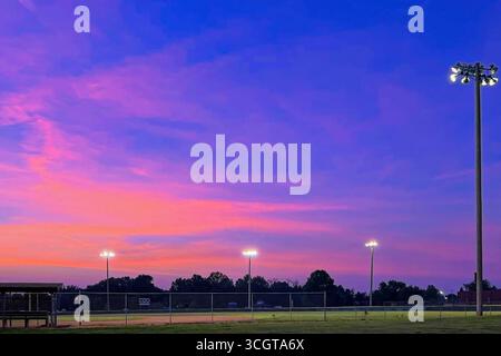 Blue and orange sunset over baseball field with field lights on Stock Photo