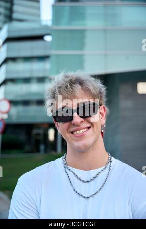Blond gen z influencer smiling wearing sunglasses and silver chains Stock Photo