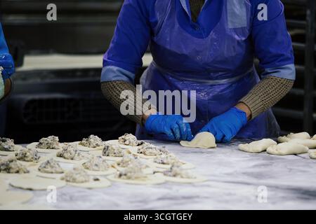 Baker kneading dough and making pies at bakery Stock Photo