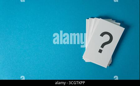 Question mark sign and symbol on white paper notes stack business and customer faqs concept on blue cyan background with copy space. Stock Photo