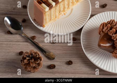 Overhead shot of a cozy, rustic coffee scene featuring a cup of espresso, cinnamon stick, pine cones and scattered coffee beans on a wooden table bath Stock Photo
