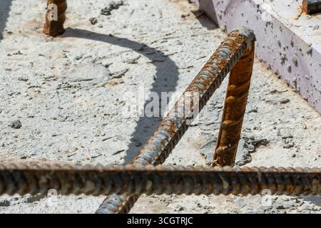 Exposed, rust, mill-scale, covered rebar that is partially encased in concrete.  A second concrete pour to cover exposed rebar. Stock Photo