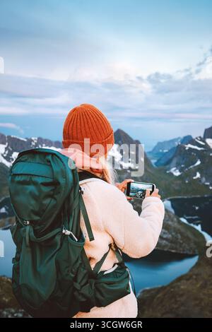 Woman using smartphone camera in mountains travel solo in Norway hiking adventure outdoor tourist blogger with backpack explore Lofoten islands, activ Stock Photo