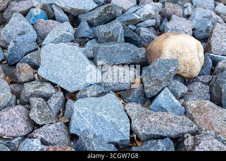 Abstract texture background view of a pile of multicolor natural granite stone rocks in natural condition Stock Photo