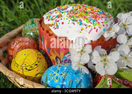 Beautiful easter easter eggs with flowers and squash in basket on grass background Stock Photo