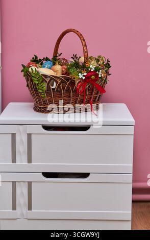 decorated Easter basket with easter and Easter eggs and sausage on a white bedside table Stock Photo