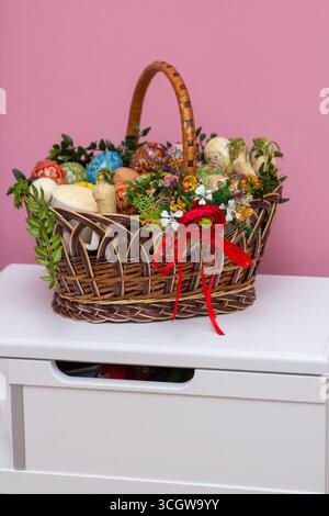 on a white bedside table there is an Easter basket with a Easter cake and a sausage and eggs Stock Photo