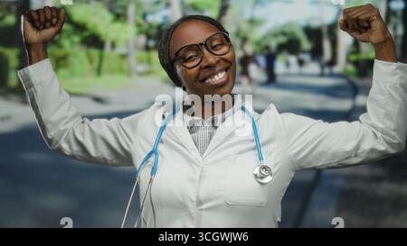 Confident doctor woman outdoor showing strength in urban environment with cheerful expression wearing glasses and stethoscope posing on city street wi Stock Photo