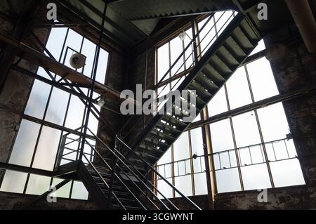 Interior of an abandoned industrial building with large glass windows. Stock Photo