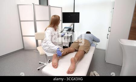 Man having foot with pain scanned using modern ultrasound machine. Ultrasound of foot and leg Stock Photo