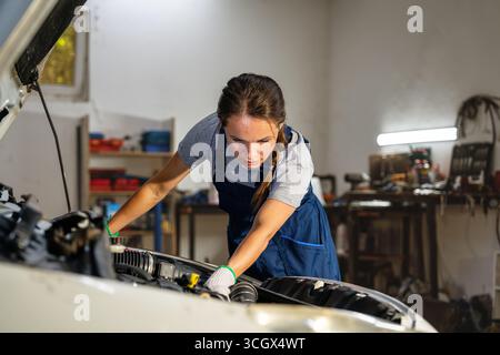 Modern young woman mechanic checking vehicle in auto service center Stock Photo