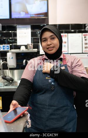 Langkawi, Malaysia - July 20, 2024: female baristas posing behind the counter at Costa Coffee, Langkawi Airport. Stock Photo