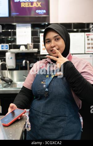 Langkawi, Malaysia - July 20, 2024: female baristas posing behind the counter at Costa Coffee, Langkawi Airport. Stock Photo