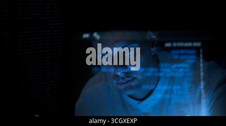 Programmers and coding. Programmer or Developer working in dark room with computer code reflected on their monitor. Cybersecurity software development Stock Photo