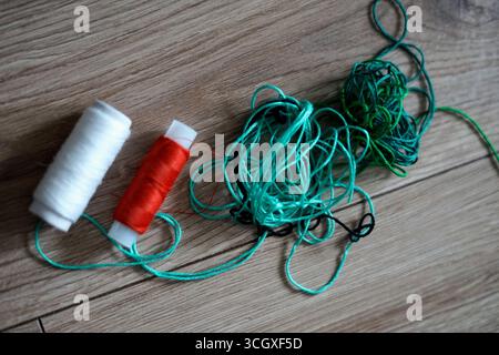 Colorful Threads and Spools Arranged Neatly on a Wooden Surface Stock Photo