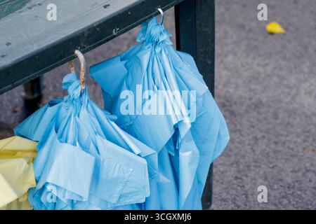 Two blue umbrellas hang from a metal rail to dry on a rainy day. A close-up of a common sight after a downpour. Stock Photo