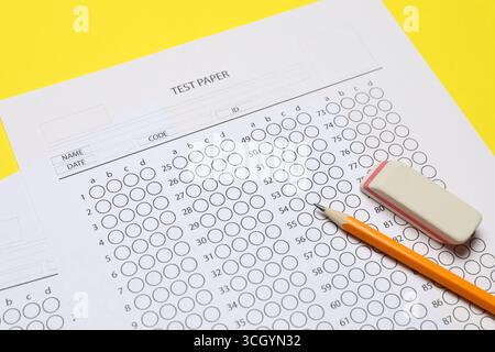 Answer sheet, pencil and eraser on yellow background, closeup. Student passing exam Stock Photo